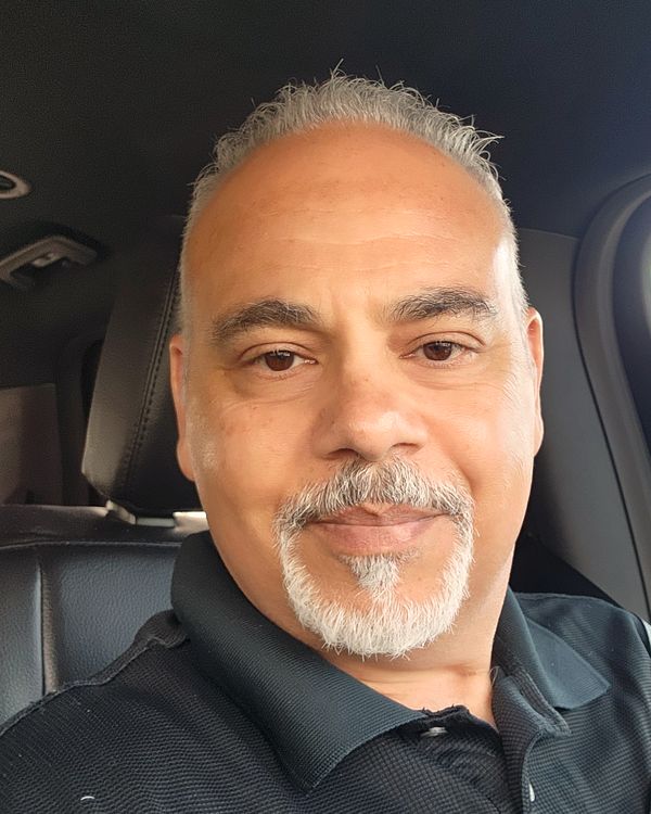 Glenn Mehterian, owner of Lion’s Heart Social, smiling, with short gray hair and a gray goatee, wearing a dark polo shirt
